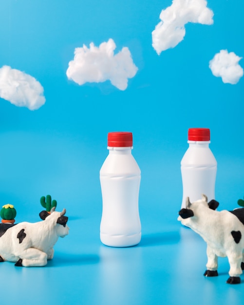 Botellas de leche de plástico, vacas de juguete y nubes.