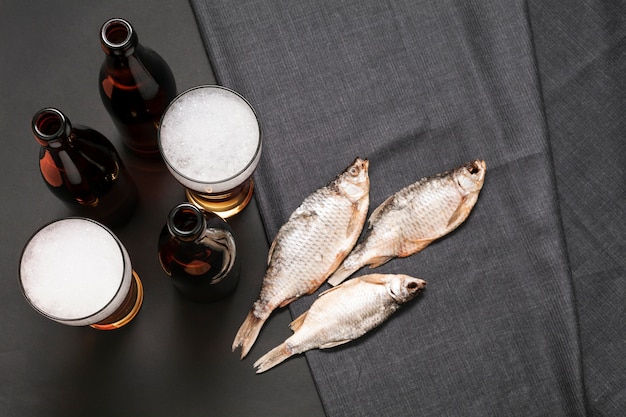 Botellas planas y vasos de cerveza con pescado
