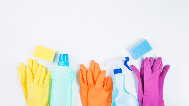 Botellas de plástico con guantes y esponja sobre fondo blanco