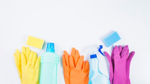 Botellas de plástico con guantes y esponja sobre fondo blanco