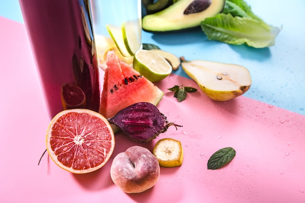 Botellas de vidrio con bebidas naturales en una pared de color