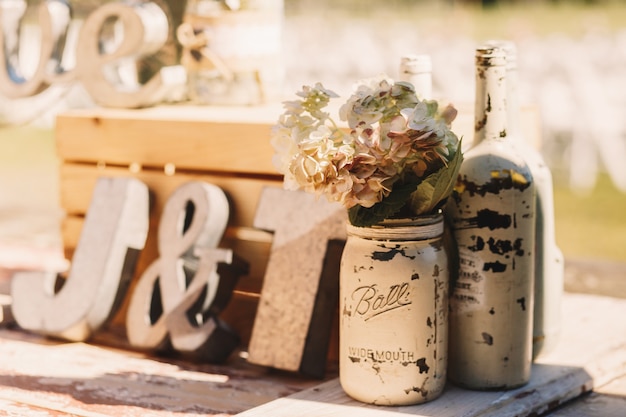 Botellas viejas blancas con flores beige de pie antes de madera