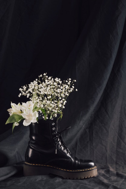 Bouquet de flores blancas en bota de cuero oscuro.