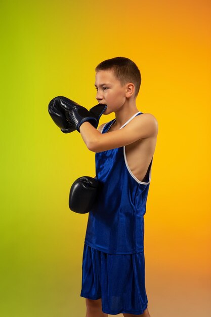 Boxeador adolescente contra el estudio de neón degradado en movimiento de patadas, boxeo