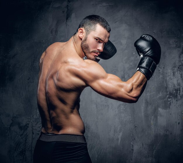 Boxeador sin camisa agresivo sobre fondo gris. foto de estudio