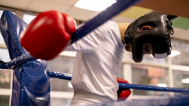 Boxeador masculino con casco y guantes en el ring practicando