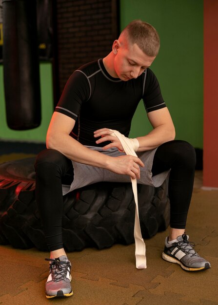 Boxeador masculino envolviendo sus manos antes de hacer ejercicio