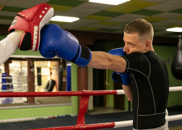 Boxeador masculino con guantes haciendo ejercicio con entrenador