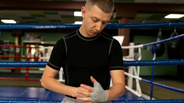 Boxeador masculino junto al anillo envolviendo sus manos con protección