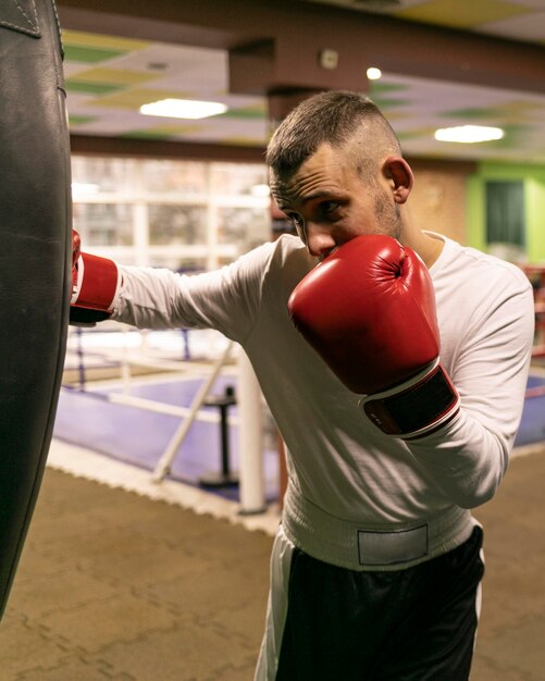 Boxeador masculino practicando con saco de boxeo