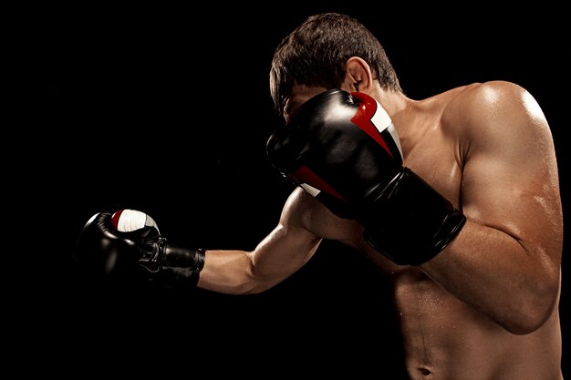 Boxeador masculino en saco de boxeo con iluminación dramática