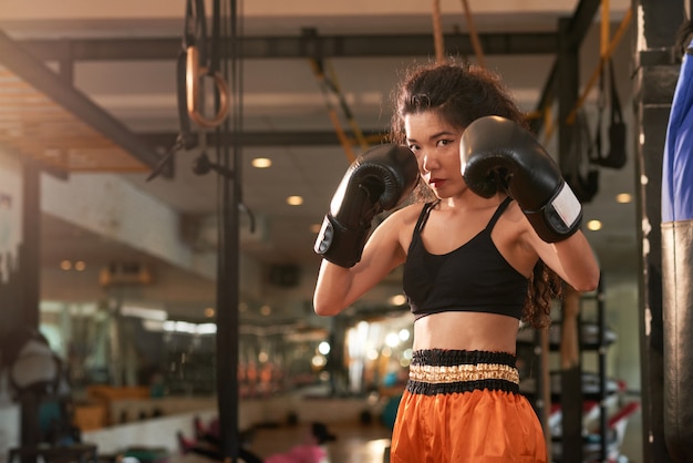 Boxeador de muay thai mirando a la cámara listo para dar un golpe