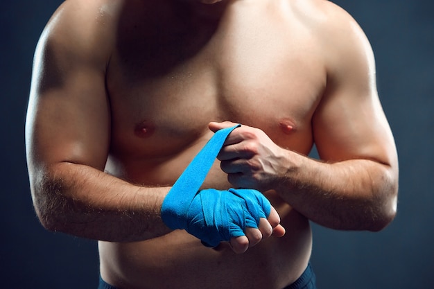 Boxeador muscular vendar sus manos en gris
