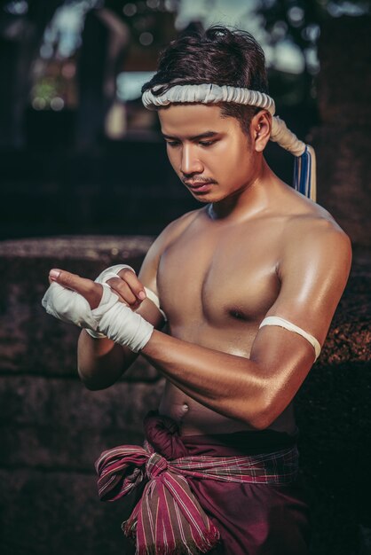 El boxeador se sentó en la piedra, ató la cinta alrededor de su mano, preparándose para pelear.