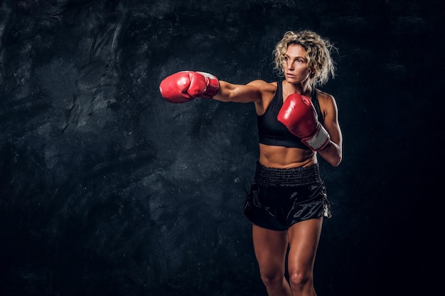 La boxeadora rubia experimentada está demostrando su ataque táctico con guantes especiales.