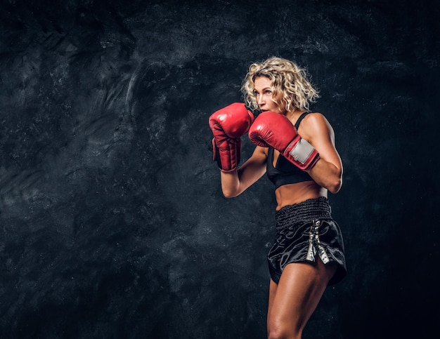 La boxeadora rubia experimentada está demostrando su ataque táctico con guantes especiales.