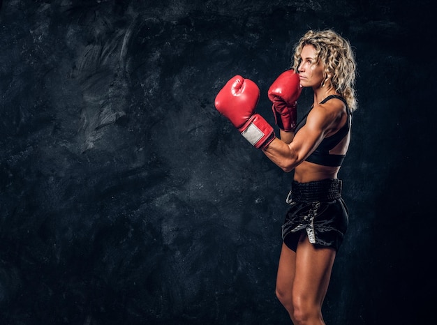 La boxeadora rubia experimentada está demostrando su ataque táctico con guantes especiales.