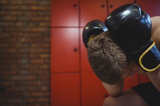 Boxer estresado sentado con guantes de boxeo