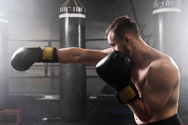 Foto gratuita boxer lateral con guantes negros de entrenamiento