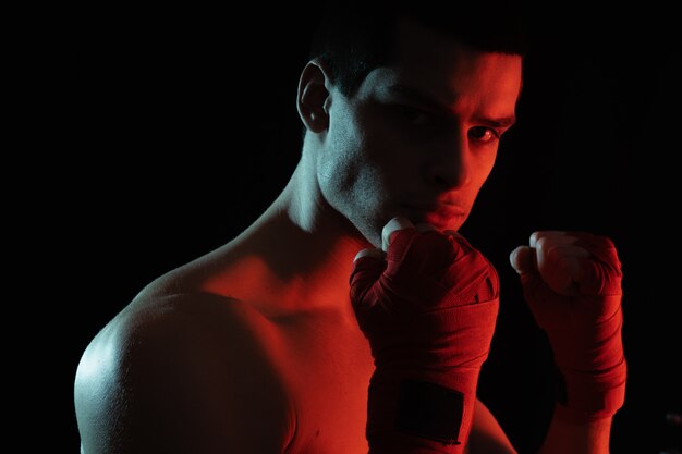 Boxer luchador masculino posando en posición defensiva segura con las manos en vendajes