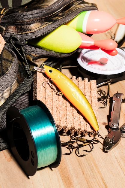 Boya en bolsa; Señuelos de pesca y carretes de pesca en el escritorio de madera.