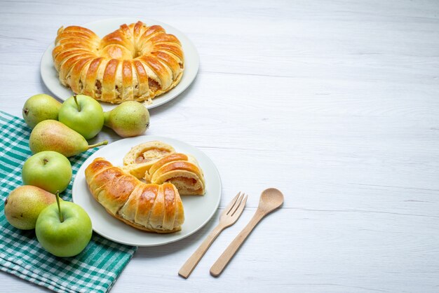 Brazalete de pastelería deliciosa horneada formada dentro de la placa de vidrio junto con manzanas y peras en el escritorio blanco, galleta de pastelería dulce hornear galleta