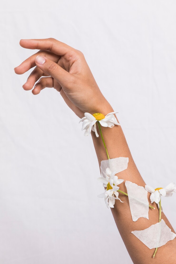 Foto gratuito brazo con flores de margarita enyesadas.