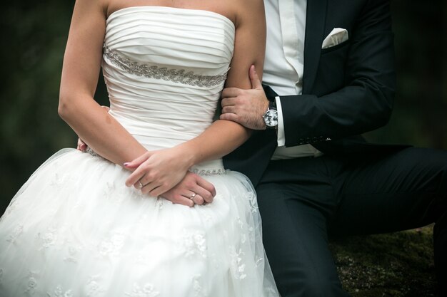 Brazo de hombre agarrando el brazo de una mujer con vestido de novia