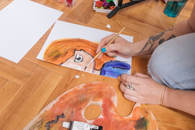 Foto gratuito brazos tatuados de mujer pintando en suelo.
