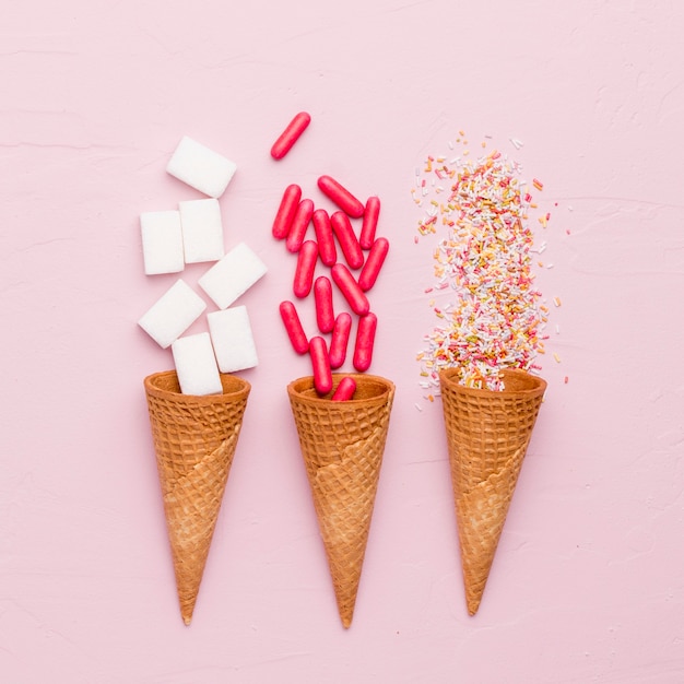 Foto gratuita brillante composición de aderezo de azúcar pastillas rojas y conos de helado