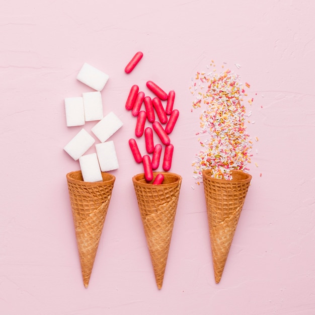 Brillante composición de aderezo de azúcar pastillas rojas y conos de helado