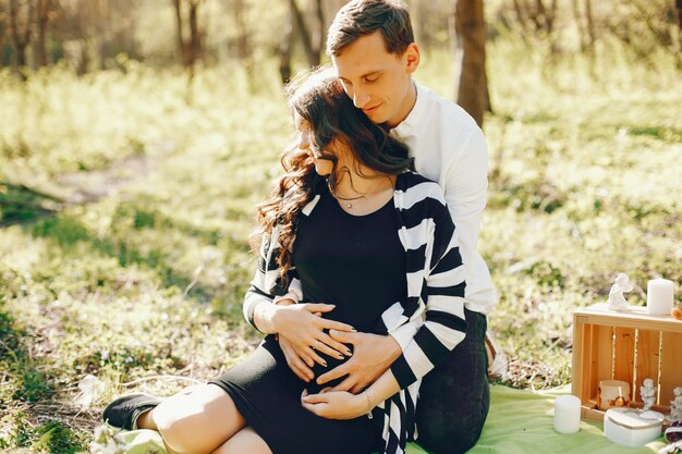 brillante y feliz mujer embarazada sentada en el parque con su marido