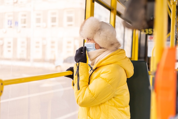 Brillante y soleado retrato de una mujer joven en ropa de abrigo en un autobús de la ciudad en un día de invierno
