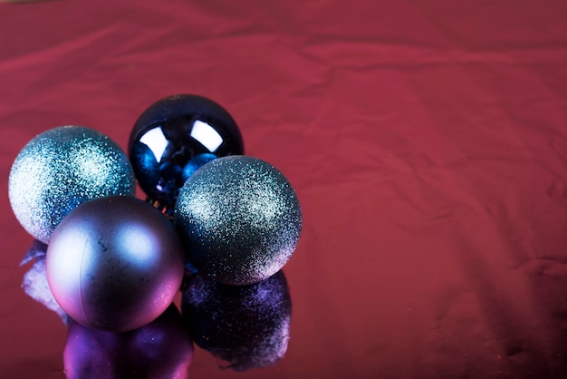 Brillantes bolas de navidad sobre tela color burdeos.