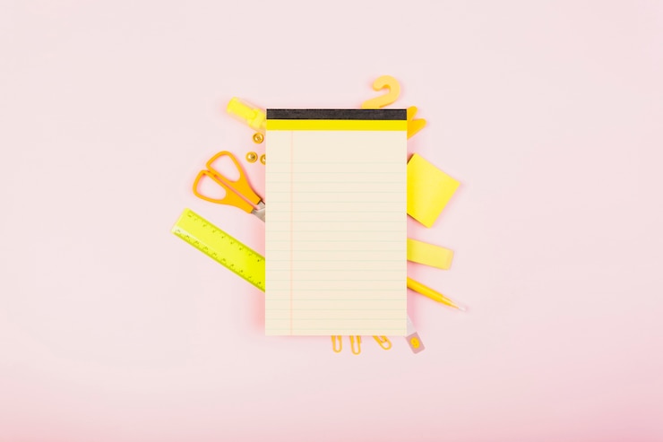 Foto gratuito brillantes suministros de oficina de color amarillo detrás de la libreta vacía