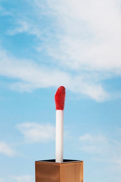 Brillo de labios rojo brillante con fondo de cielo