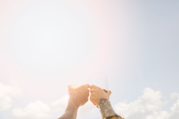 Brindando con cerveza sobre fondo de cielo