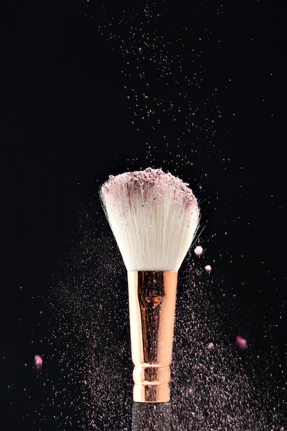 Brocha de maquillaje profesional negra con polvo rosa