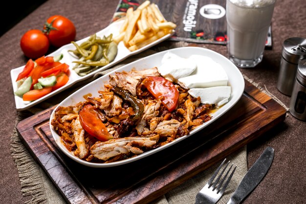 Brocheta de pollo con salsa de tomate servida con yogurt, papas encurtidas y vegetales