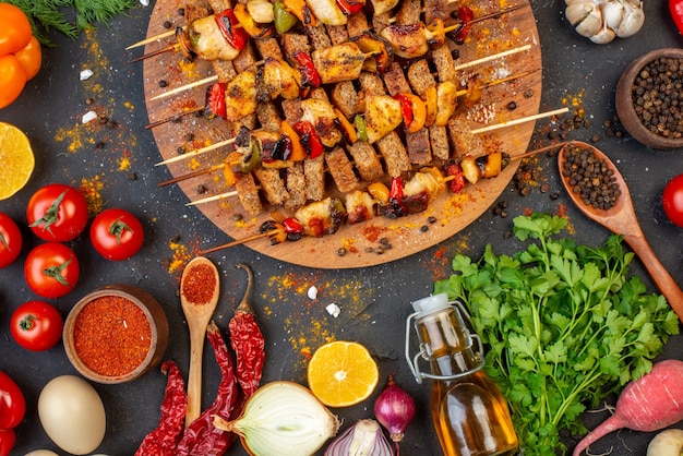 Brochetas de pollo asado a la parrilla en la mitad superior de la tabla de madera y otras cosas en la mesa