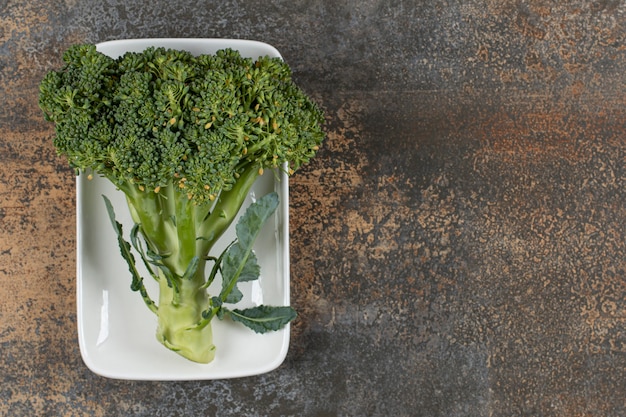 Brócoli crudo orgánico verde saludable en el recipiente sobre la superficie de mármol