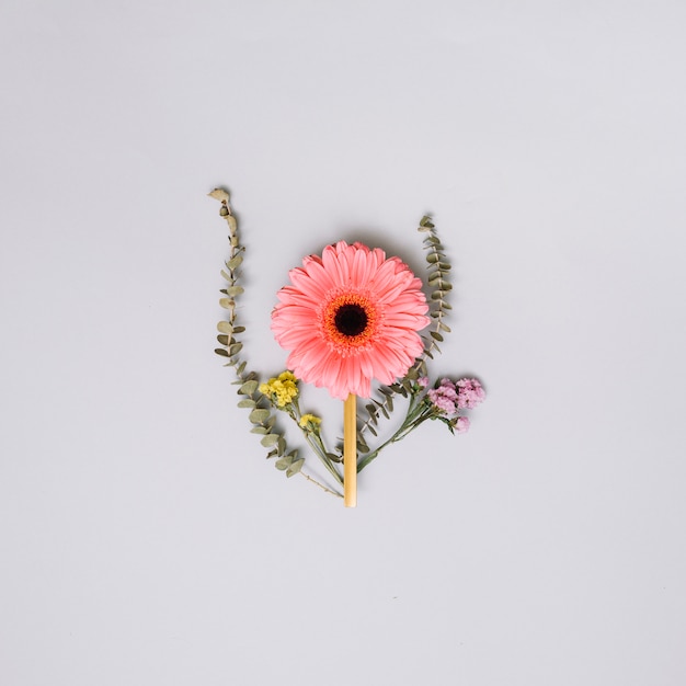 Foto gratuita brote de flor rosa con pequeñas ramas en la mesa