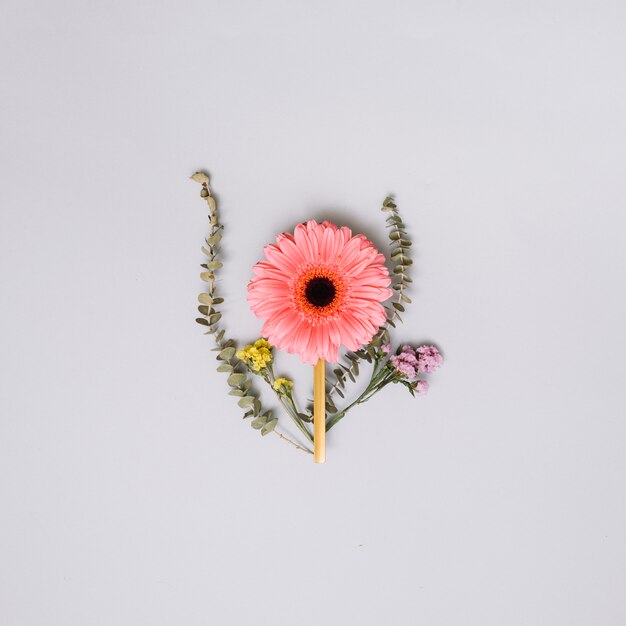 Brote de flor rosa con pequeñas ramas en la mesa