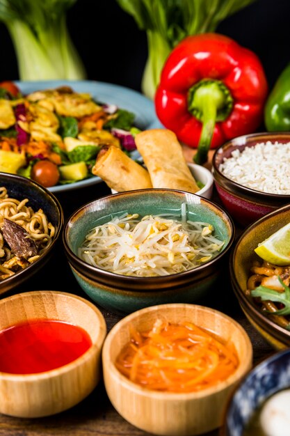 Brotes de habichuelas rodeados de ensalada; salsa; rollitos de primavera y fideos