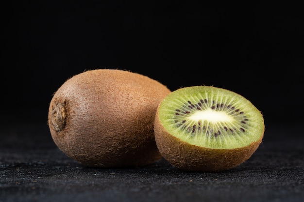 Brown kiwi fresco medio corte suave y jugoso aislado en la oscuridad