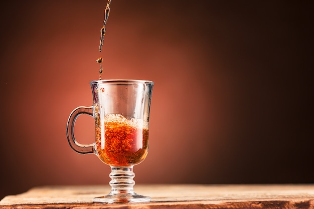 Brown salpica bebida de una taza de té en una pared marrón