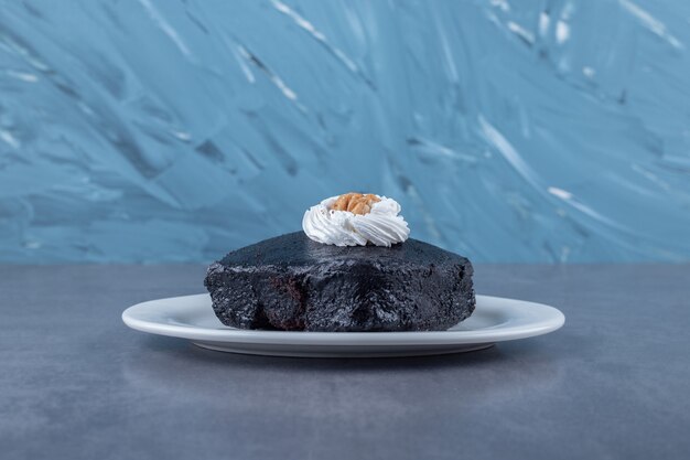 Brownie de bizcocho de chocolate húmedo en un plato sobre una mesa de mármol.