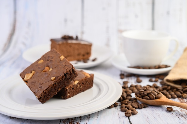 Brownie de chocolate en un plato blanco y granos de café en una cuchara de madera.