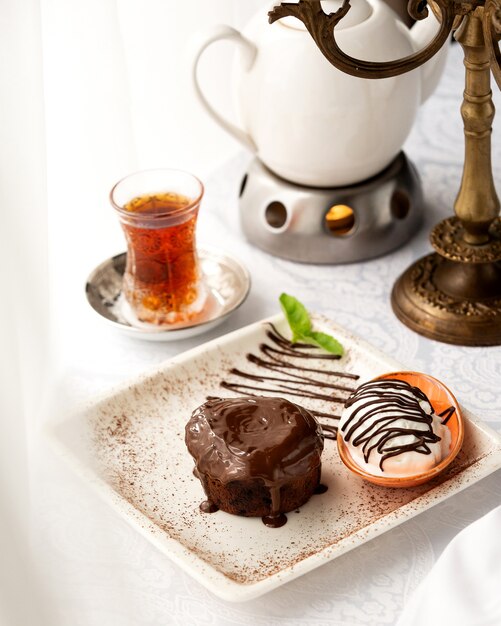 Brownie con salsa de chocolate servido con helado de vainilla y té negro