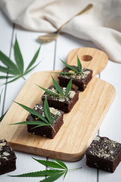 Brownies de cannabis y hojas de cannabis en tabla de cortar de madera